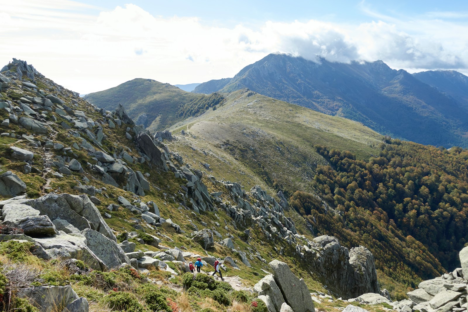 Hikers descending a granite ridge on the GR20, Corsica