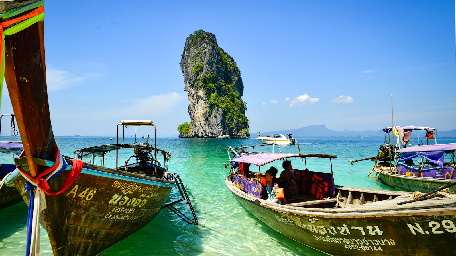 Long-tail boats by a limestone karst, Andaman coast