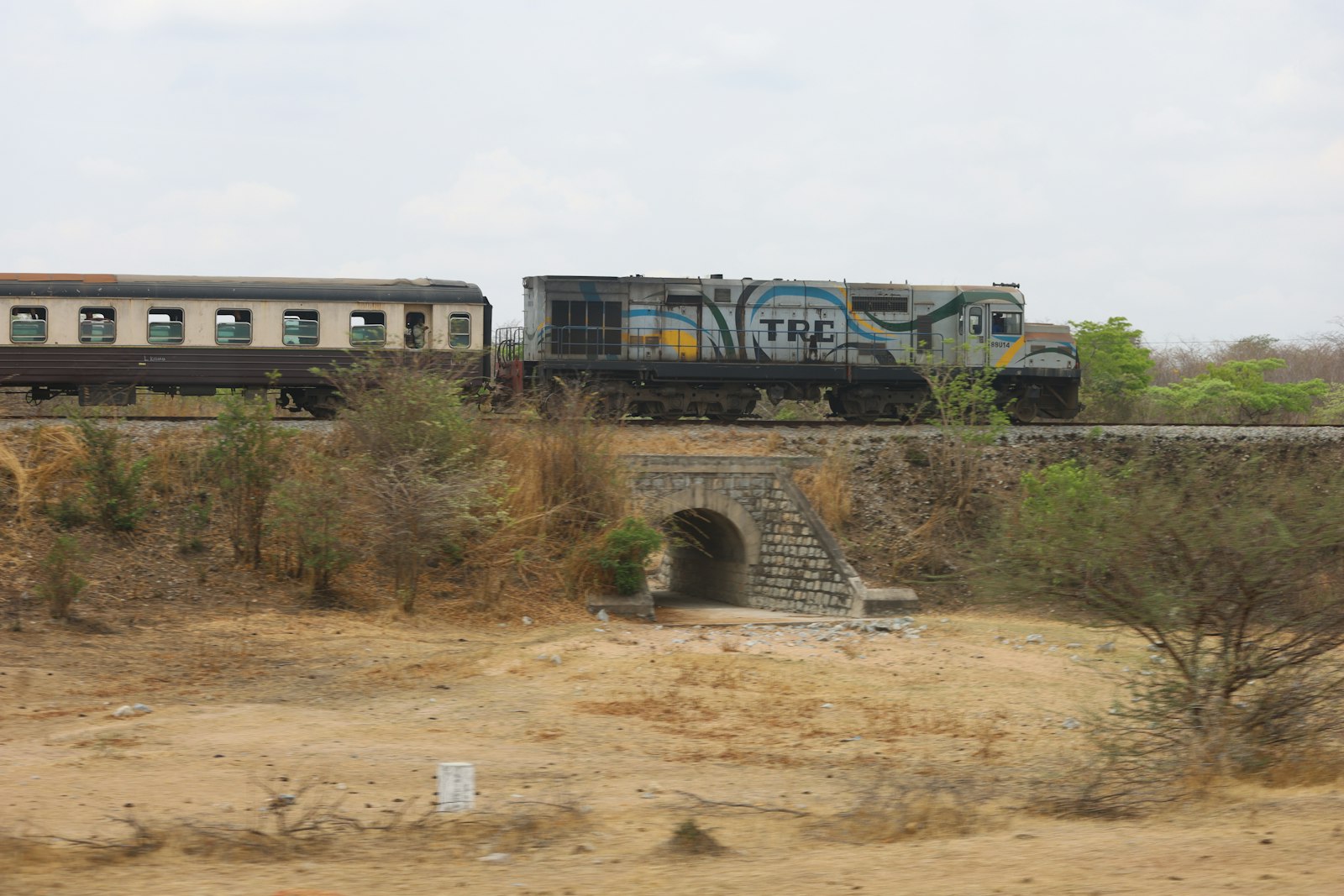 Tazara train crossing a stone bridge through savanna