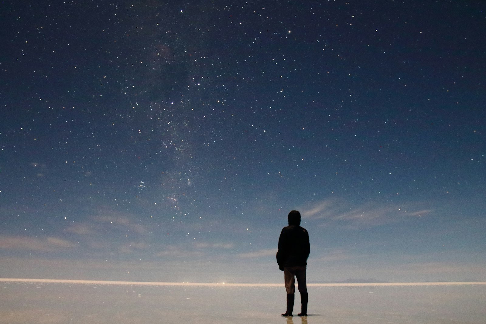 Traveller stargazing on the salt flat under the Milky Way