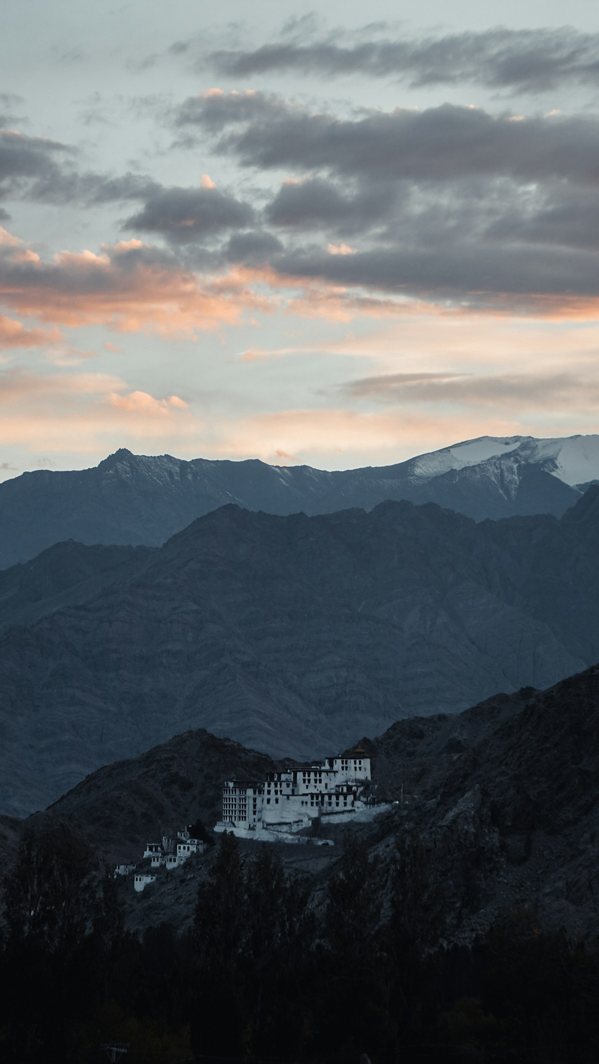 Ladakhi monastery lit at dusk beneath the Zanskar range