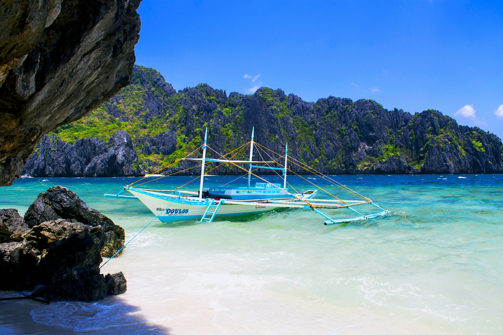 Traditional outrigger bangka boat moored on a white-sand beach